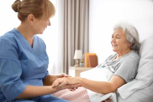 A nurse checks in with a patient in a skilled nursing facility.